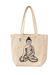 A beige canvas tote bag with a black line art illustration of a seated Buddha figure on the front, featuring a small green and white 'THREE CUPS OF TEA' logo patch on the upper left side. The bag is photographed against a clean, off-white background.