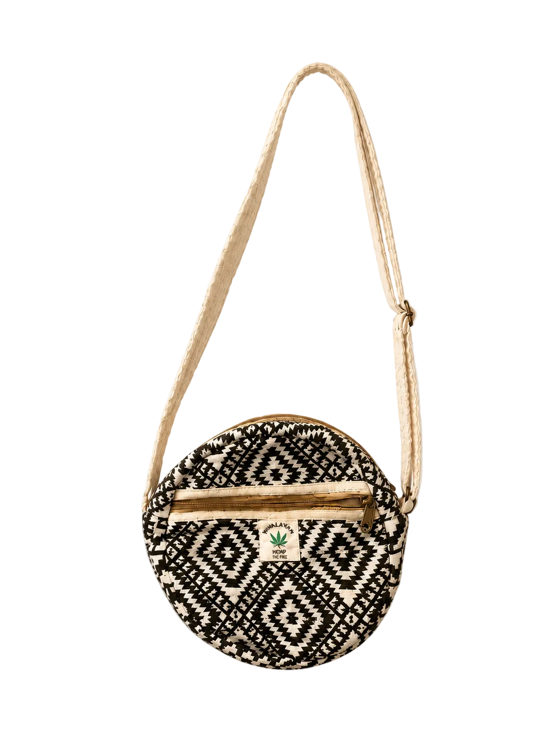 A round woven crossbody bag with a black and off-white geometric pattern, a natural jute strap, and a small green leaf logo on the front, shown against a plain off-white background.